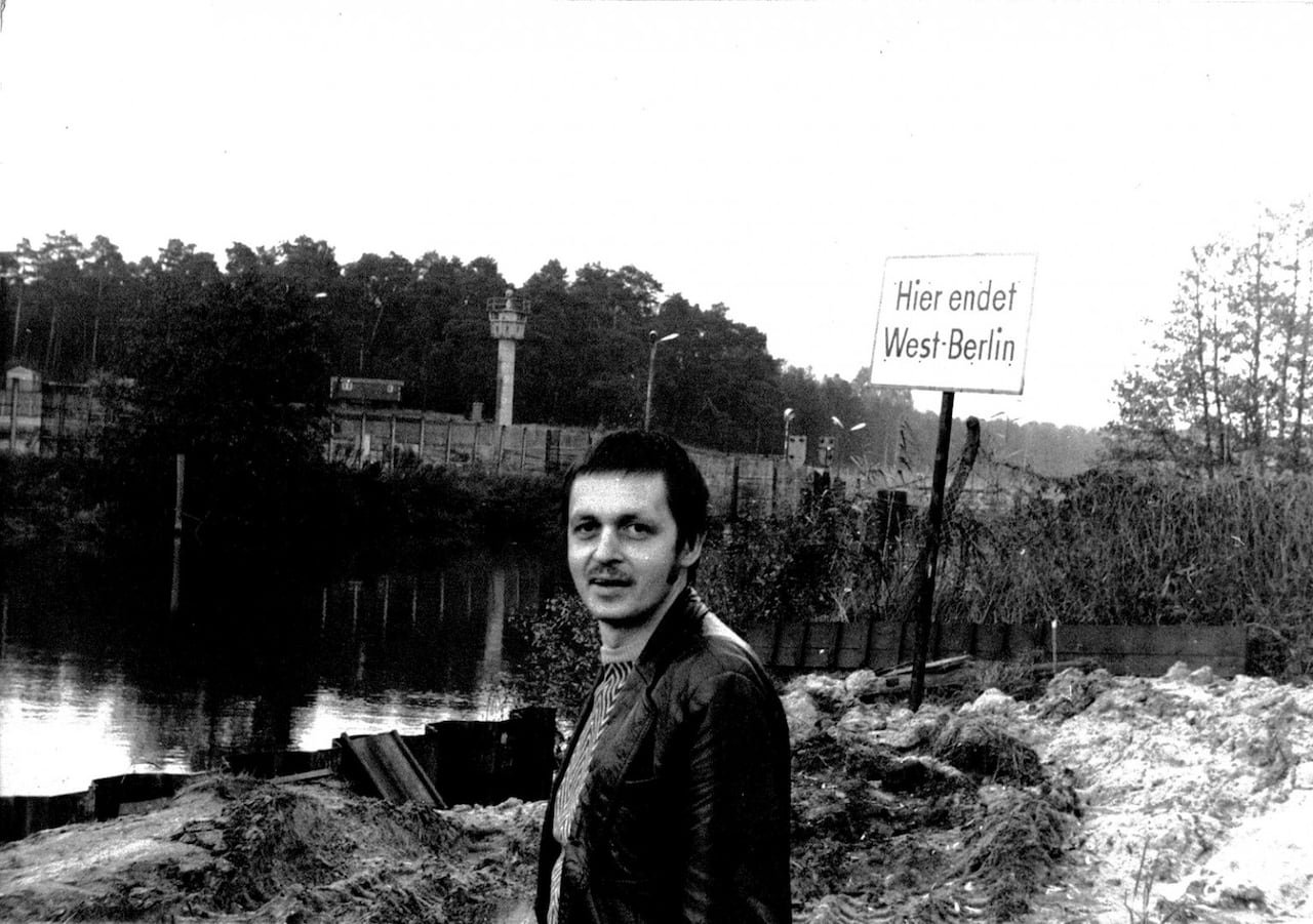 default-109 A man stands in front of the Spree river in black and white, with the Berlin wall behind him.
